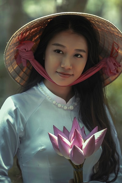 女人穿着白色长袖衣服和棕色sungat控股粉红色花瓣的花
